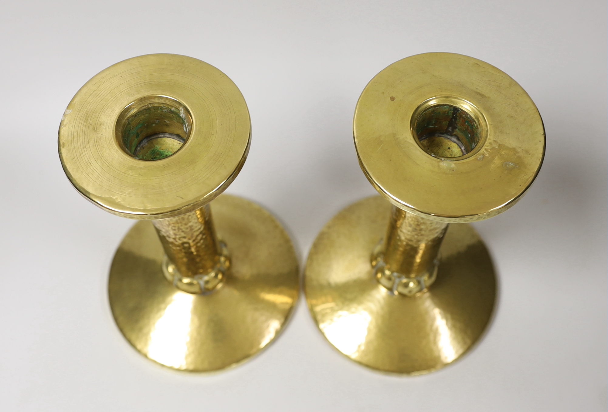 A pair of Arts and Crafts hammered brass candlesticks, with detachable sconces, 21cm